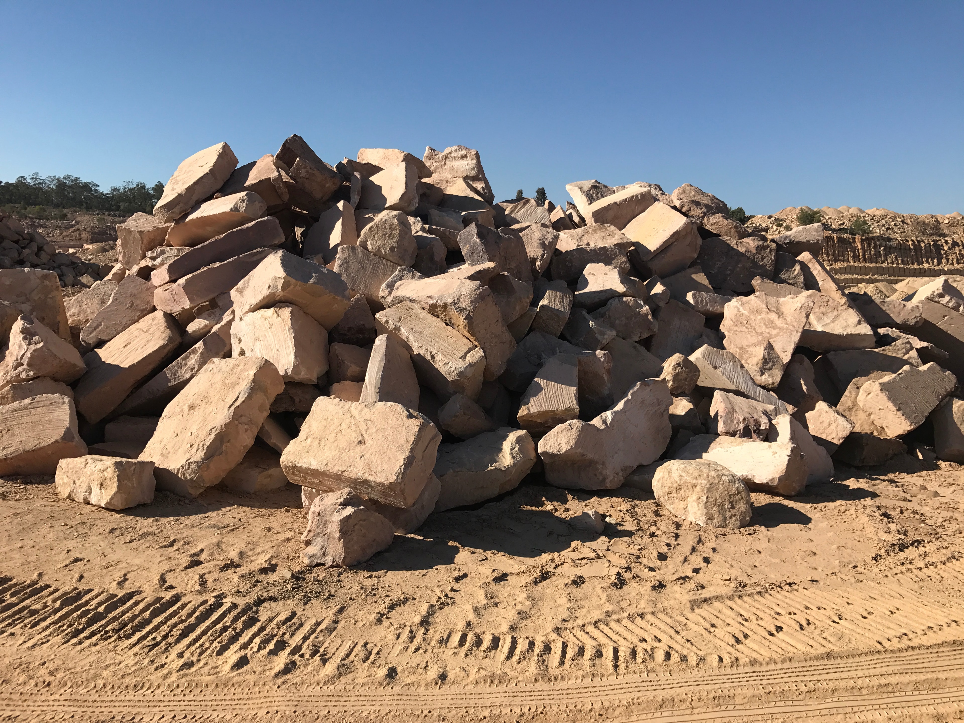 Large pile of rough-cut sandstone boulders at quarry