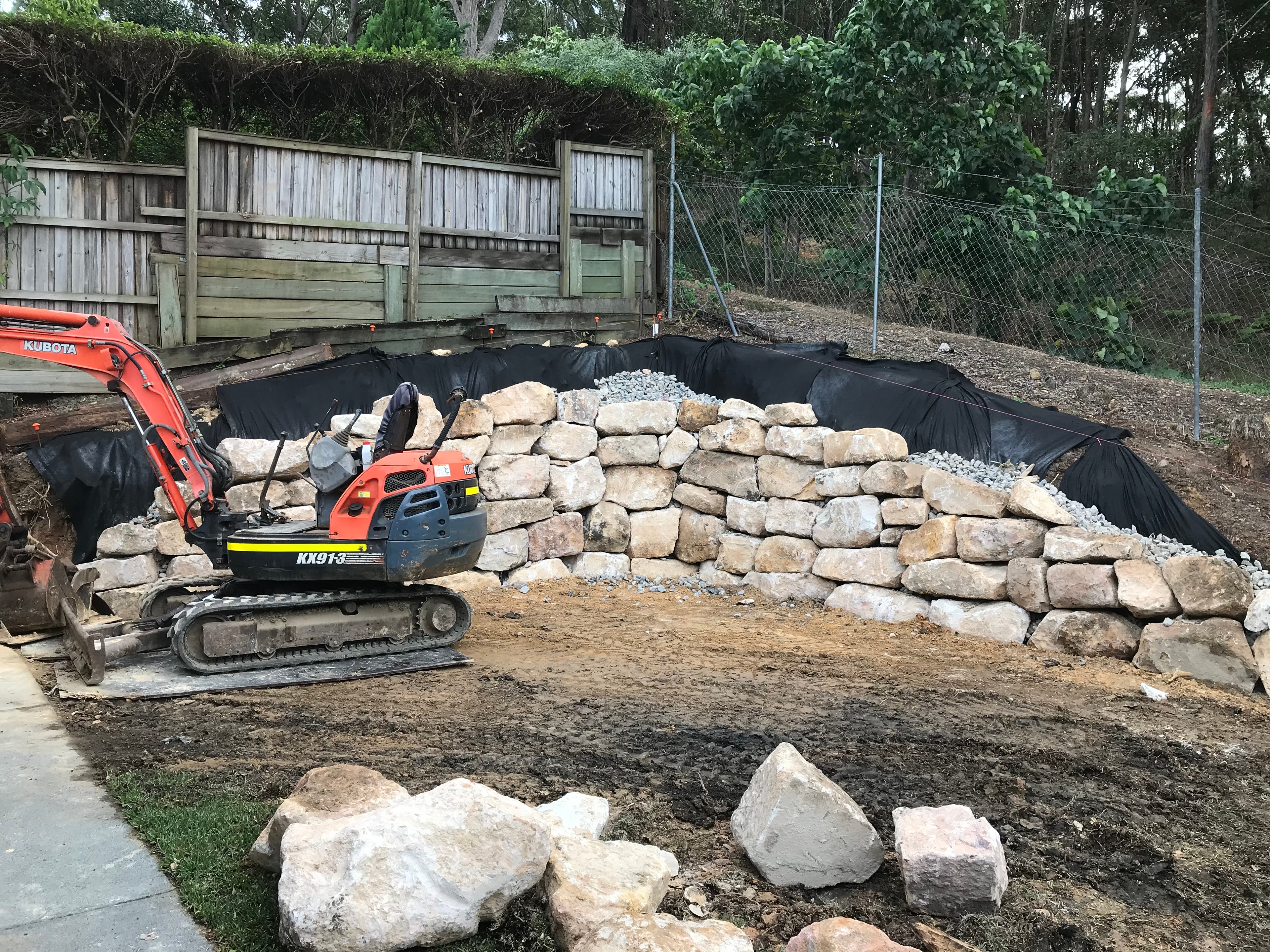 Kubota excavator beside sandstone retaining wall under construction