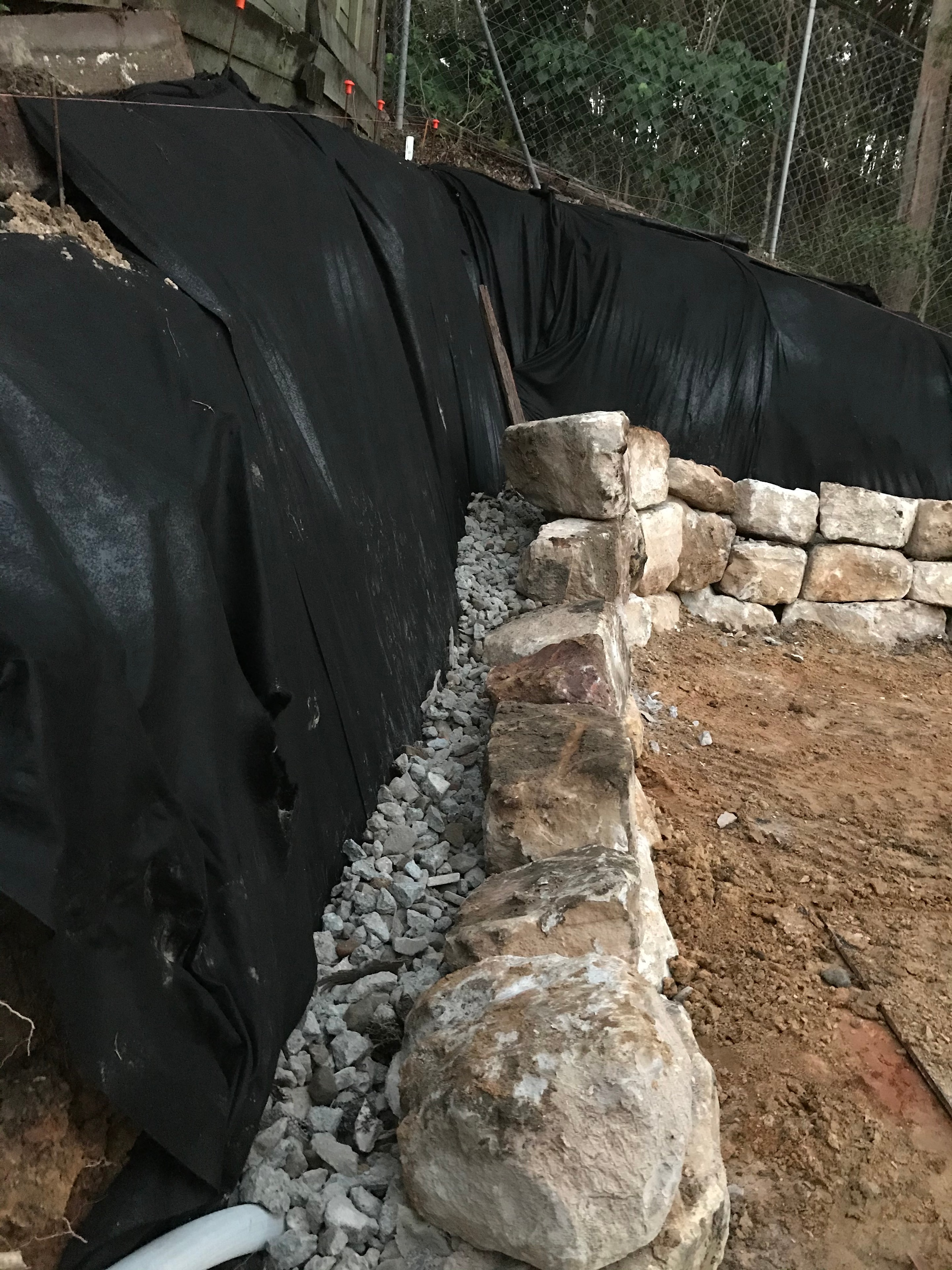 Stone blocks and gravel with landscape fabric during wall build