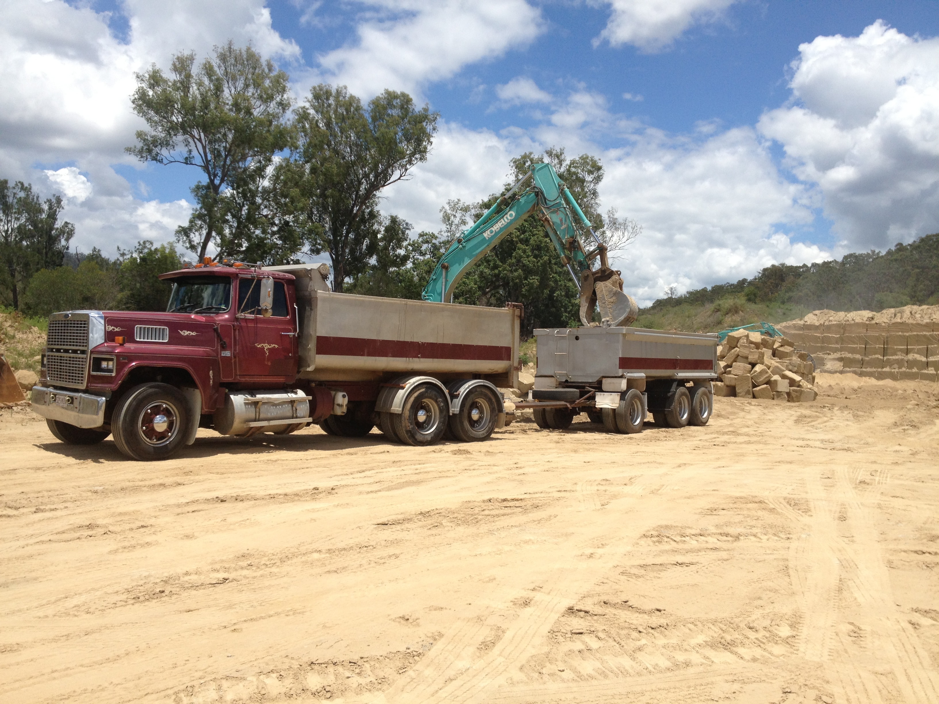 Kobelco excavator and Ford dump truck at sandstone excavation site