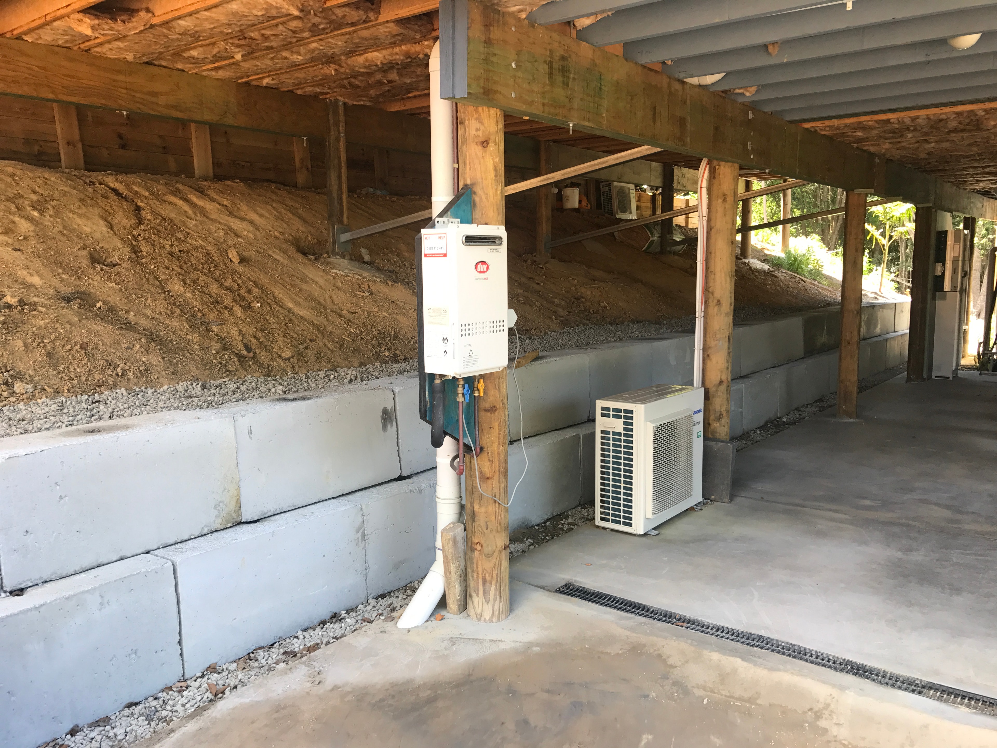 Concrete block retaining wall under house with HVAC equipment