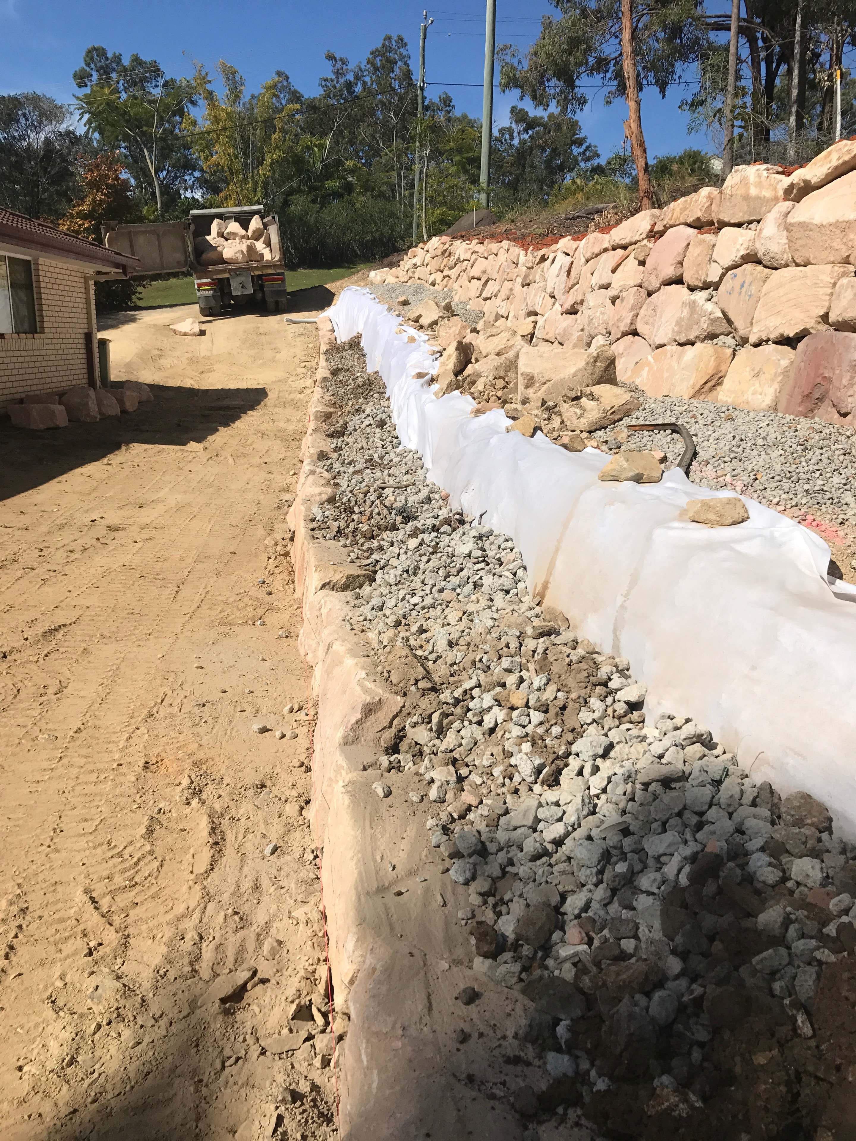 Rock wall construction with geotextile fabric and gravel drainage